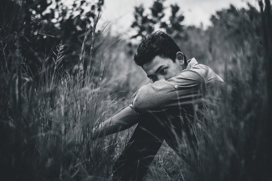 A man sitting alone outdoors, lost in thought